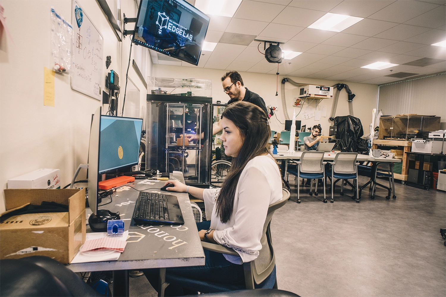 Honors student in a lab looking a computer screen in the lab
