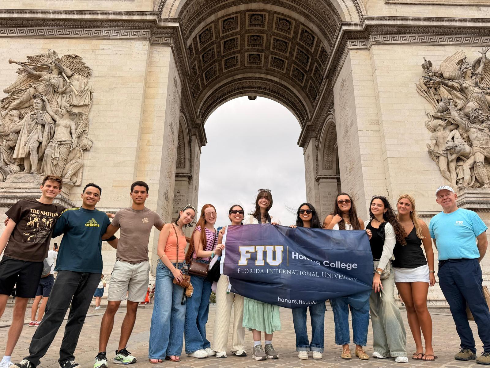 Students in front of the Arc de Triomphe holding the FIU Honors College flag in Paris