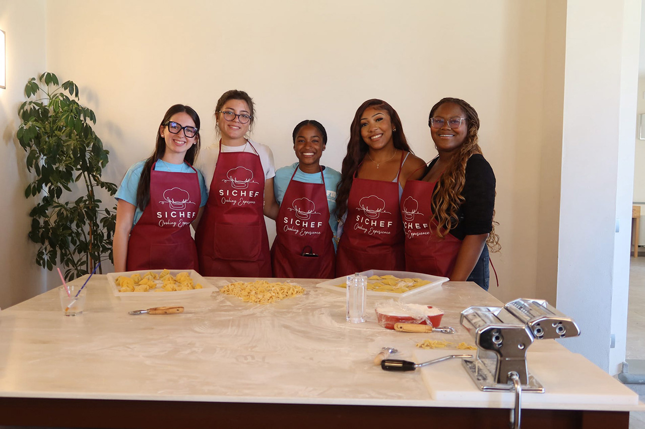 FIU Study Abroad Honors students holding a program banner in an Italian ballroom